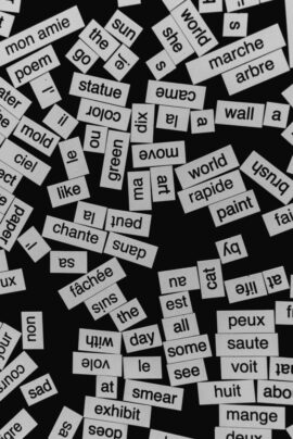 A close-up of various word cutouts on a black background, featuring different languages.