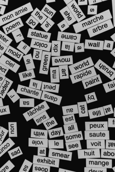 A close-up of various word cutouts on a black background, featuring different languages.